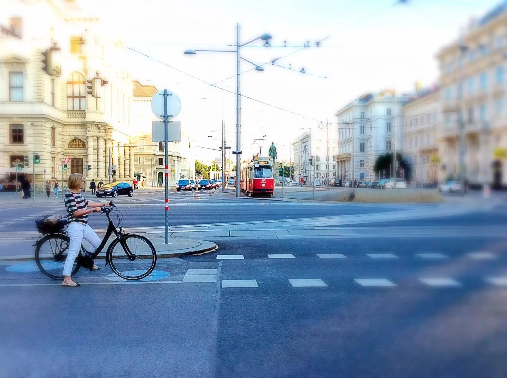 Cyclist waiting at a crossing at Schwarzenbergplatz with a Vienna tram approaching in evening light.