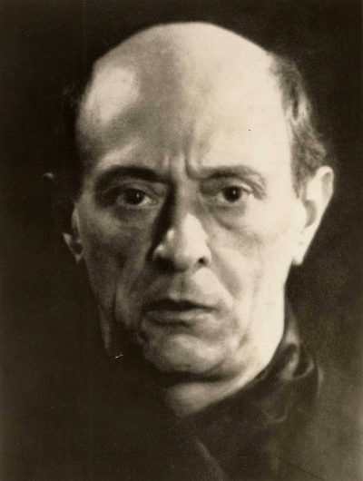 Close-up black-and-white portrait of a middle-aged man with a high forehead and receding hairline, looking directly at the camera with a serious expression.