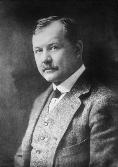 Black-and-white studio portrait of composer Franz Lehár wearing a dark suit, waistcoat and tie, with neatly combed hair and a moustache.