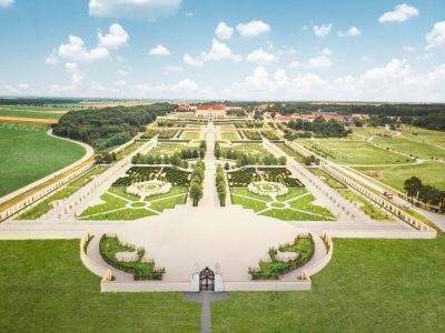 Elevated view of Schloss Hof in Lower Austria, showing the Baroque palace at the far end of a vast sequence of symmetrical terraces, formal gardens, paths, woodland and surrounding farmland.