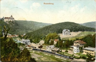 Historical colour postcard of Rosenburg in the Kamptal, with a steam train passing through the valley beside the station, villas and guesthouses, while Schloss Rosenburg rises above wooded hills.